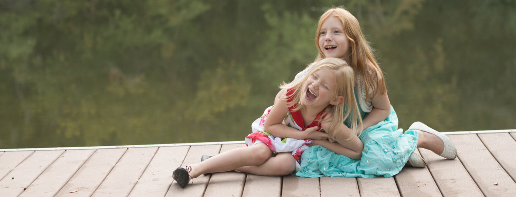 two young sisters sitting on a dock together