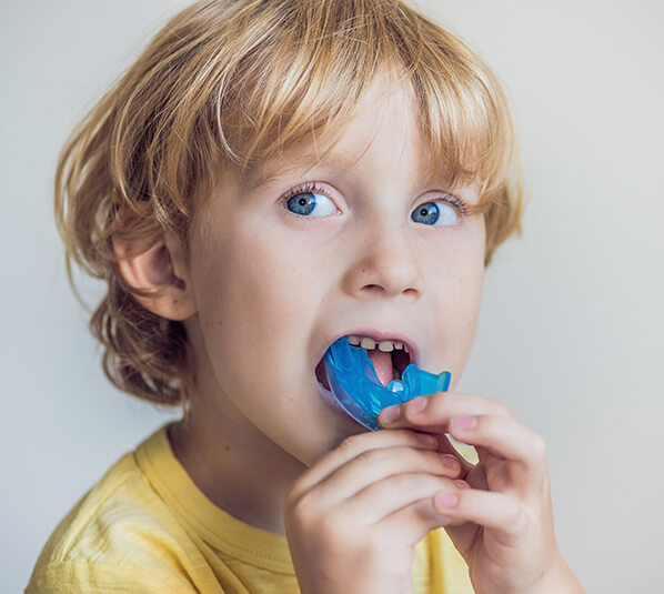 young boy putting a mouthguard on